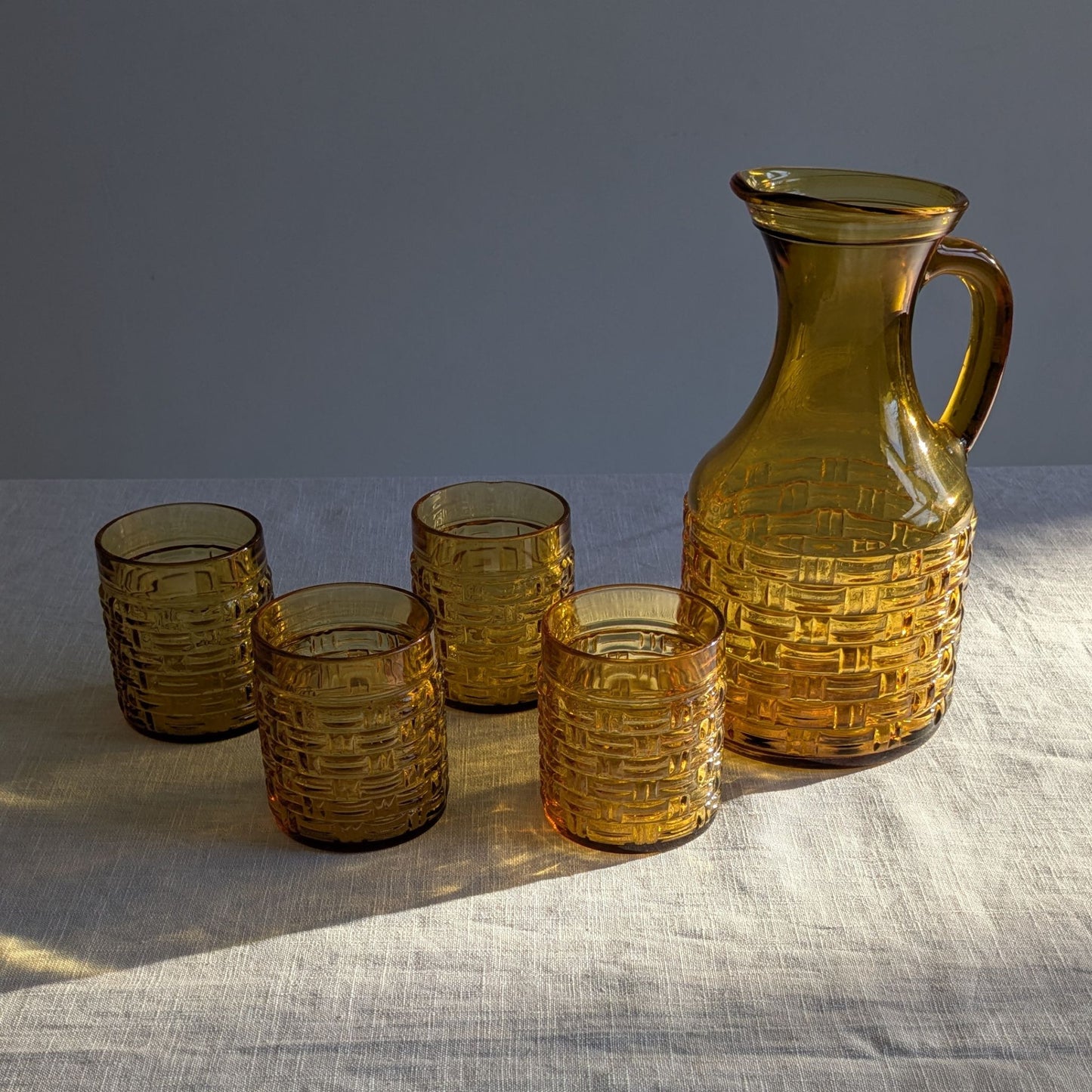 Amber glass itcher and glasses in sunlight with shadows