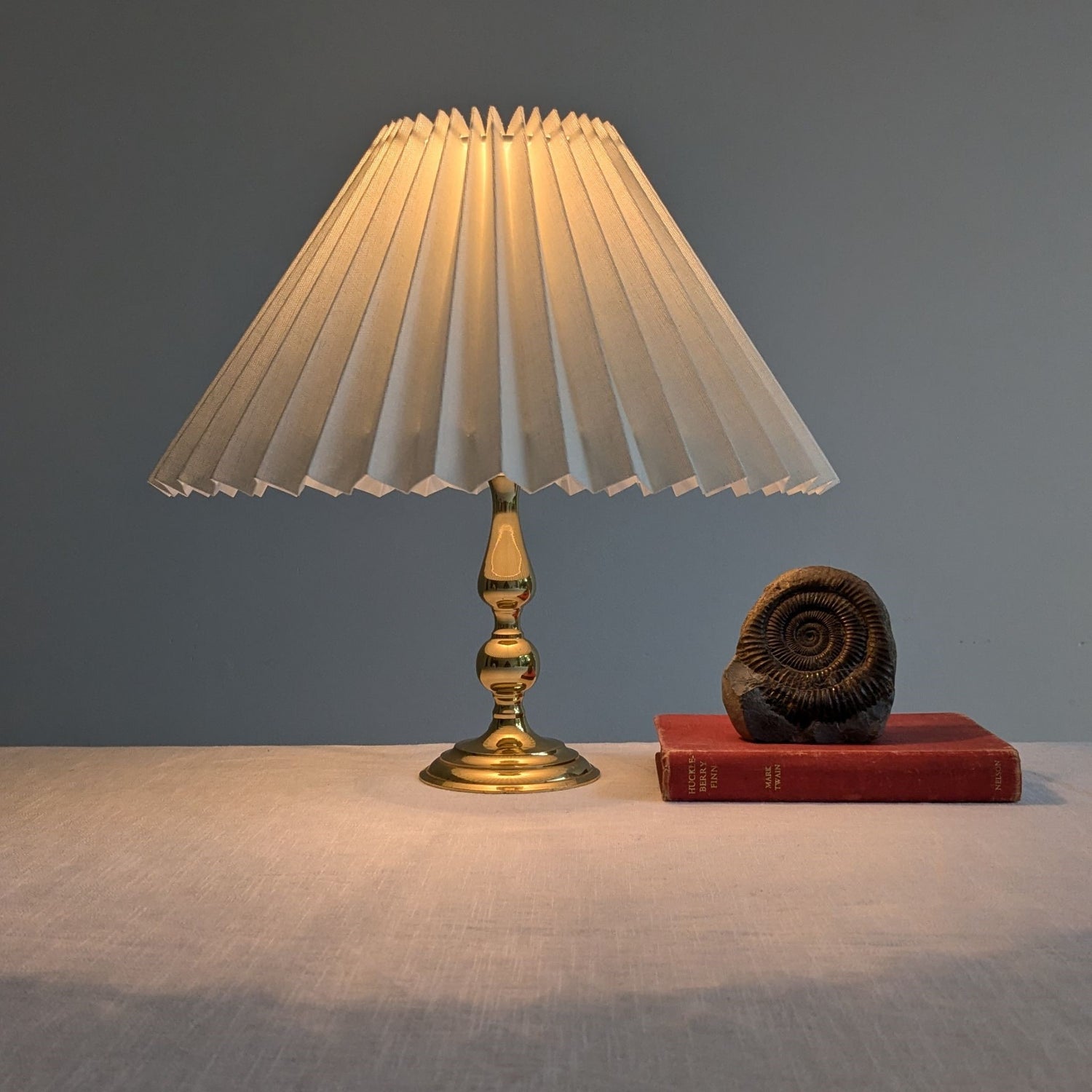 A vintage brass table lamp with a pleated paper shade