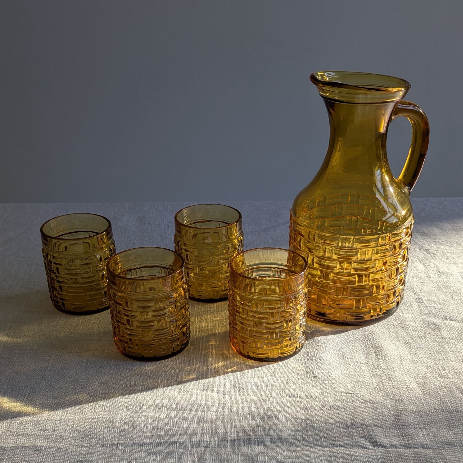 Amber glass itcher and glasses in sunlight with shadows