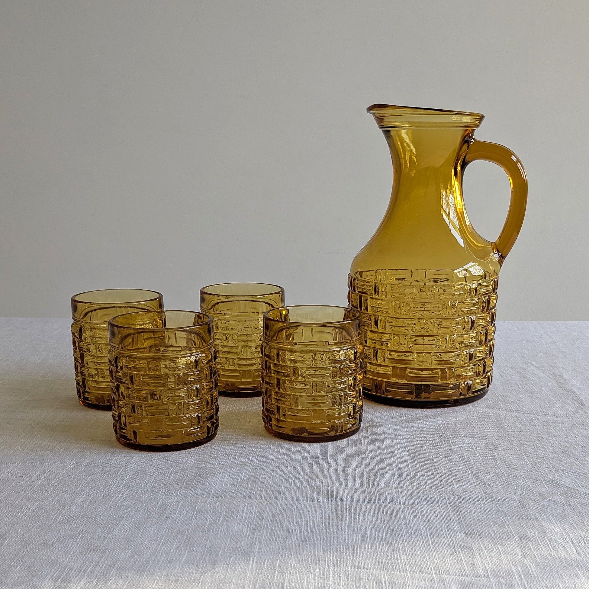 Amber glass jug and four glasses on a white background