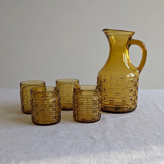 Amber glass jug and four glasses on a white background