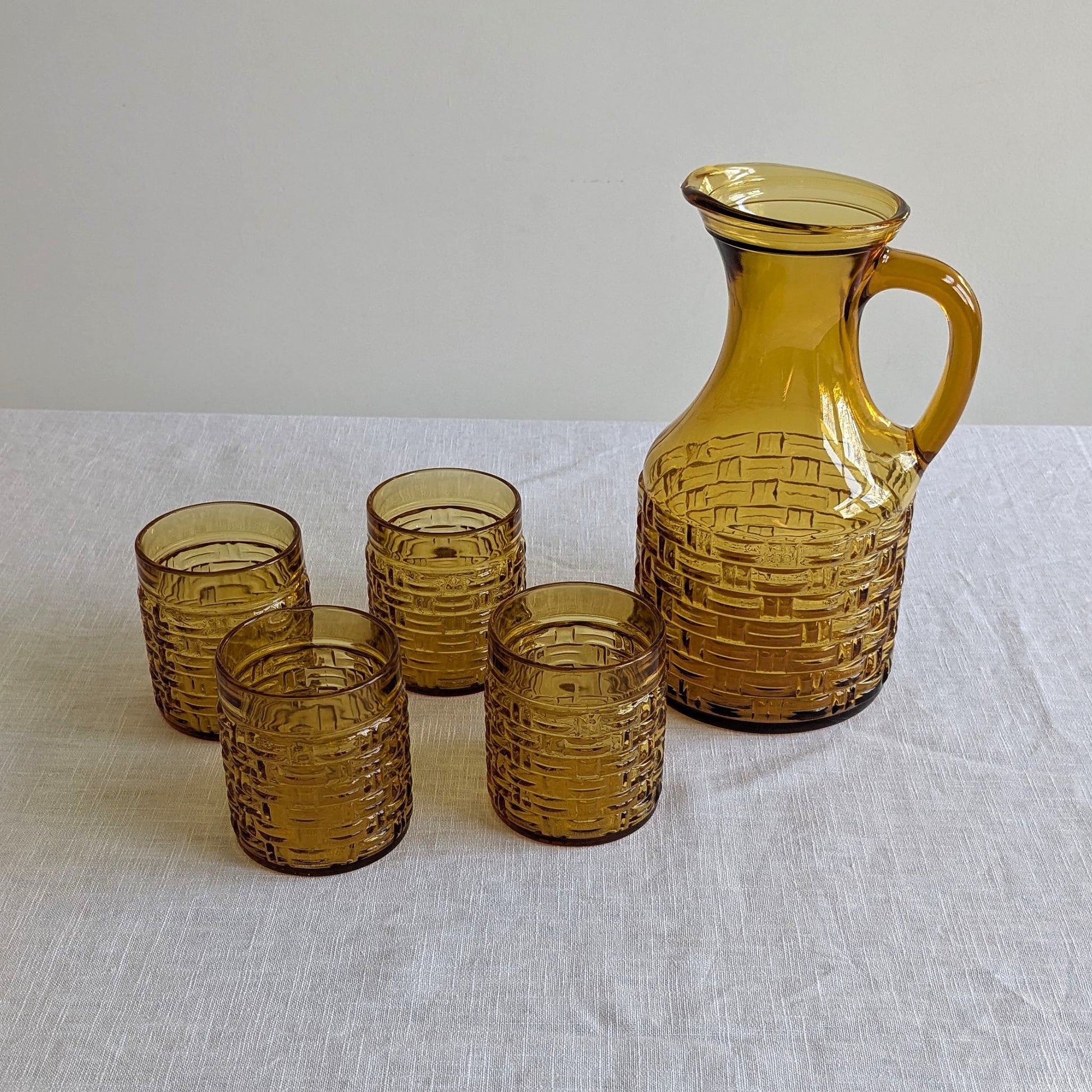 Yellow glass jug and glasses with a basket weave pattern, above view