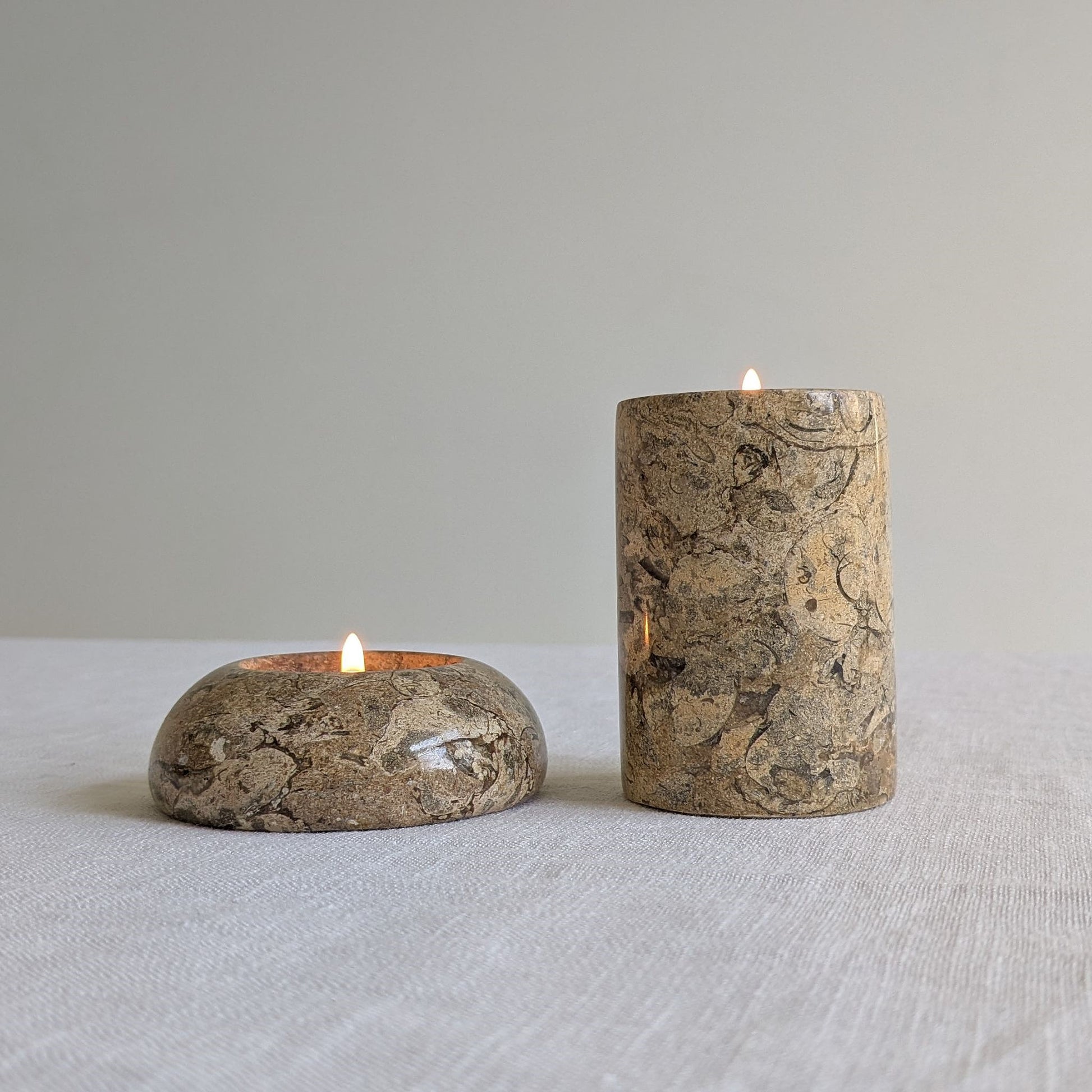 Two fossil stone tealight holders with lit tealights