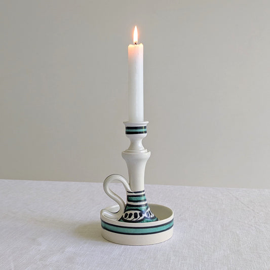 Tall white ceramic candle holder with a lit candle